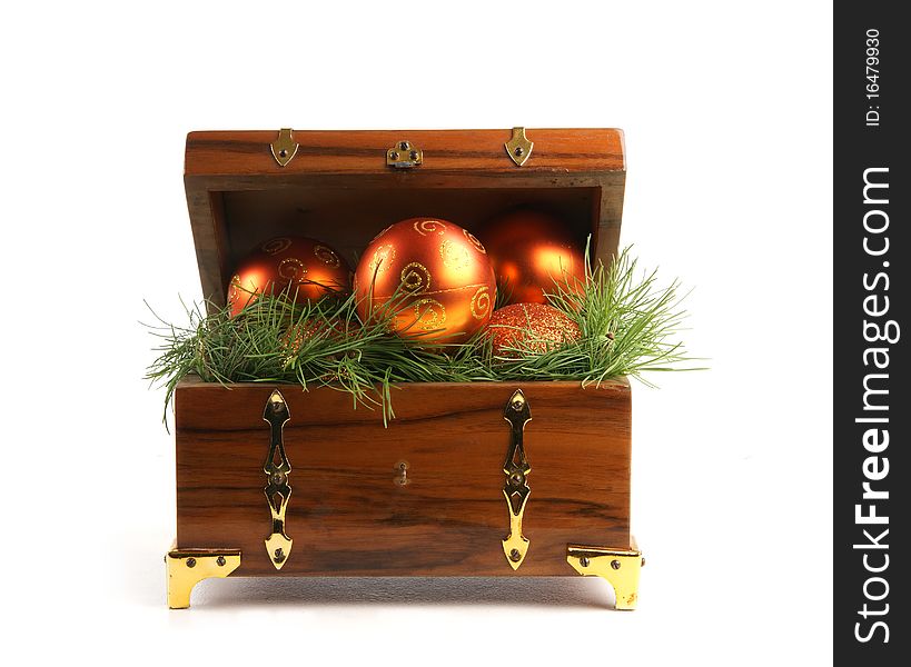 An ancient brown treasure chest full of spruce needles and Christmas balls. The image is isolated on a white background. An ancient brown treasure chest full of spruce needles and Christmas balls. The image is isolated on a white background.