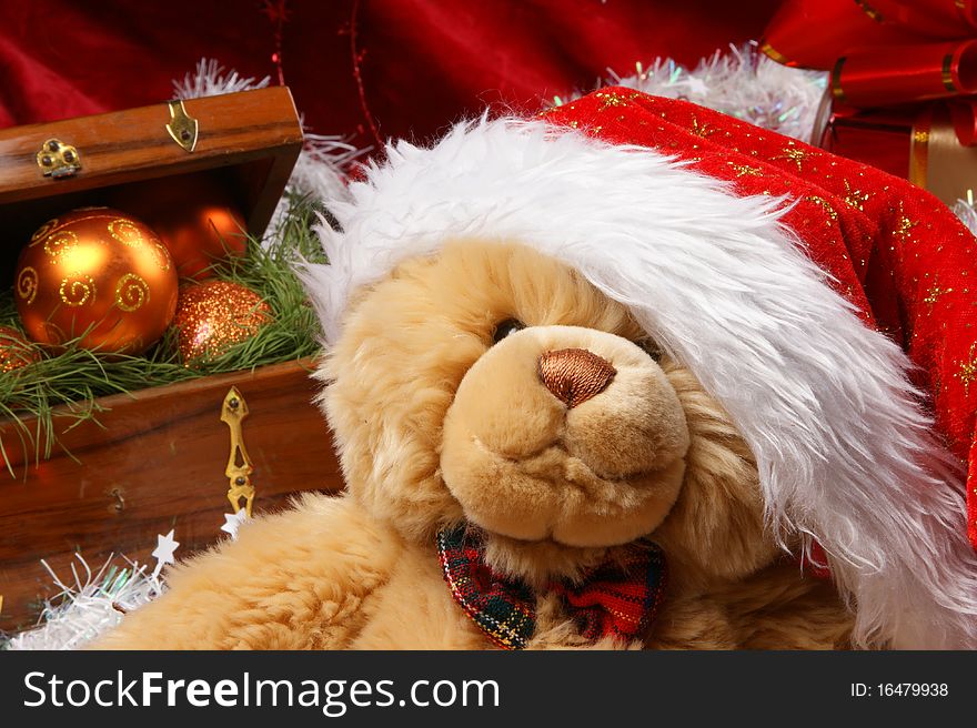 Christmas image of a cute teddy bear in a red Christmas hat. Evening balls and spruce needles are added to the background. Christmas image of a cute teddy bear in a red Christmas hat. Evening balls and spruce needles are added to the background.