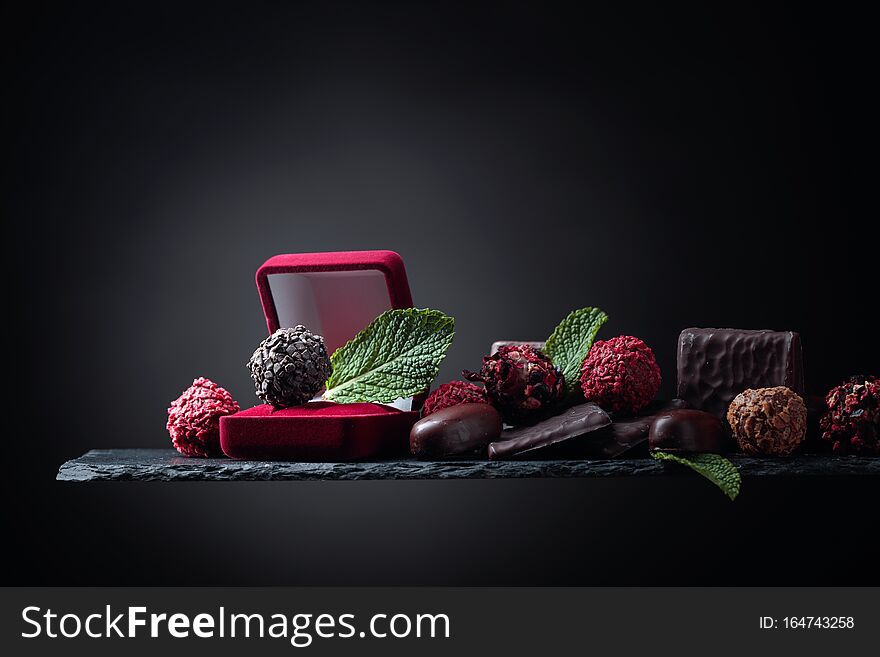 Chocolate truffle in red gift box. Various chocolates with mint. Copy space