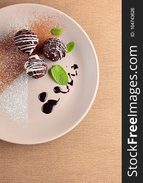 Chocolate balls with mint on a beige plate. Copy space