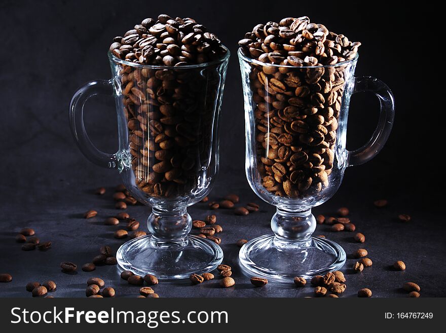 Two glasses full of coffee beans with cinnamon agaist dark background as a concept of coffee drinking. Two glasses full of coffee beans with cinnamon agaist dark background as a concept of coffee drinking