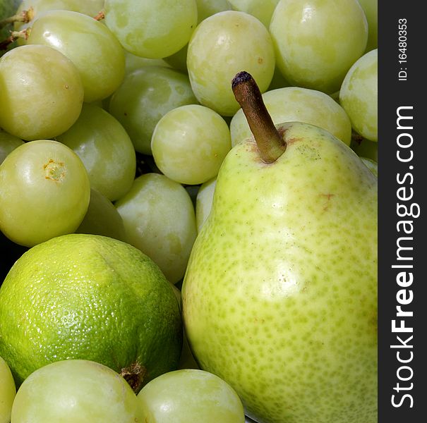 A set of different healthy and tasty green fruits. Composition consists of grapes, a lime and a peach.