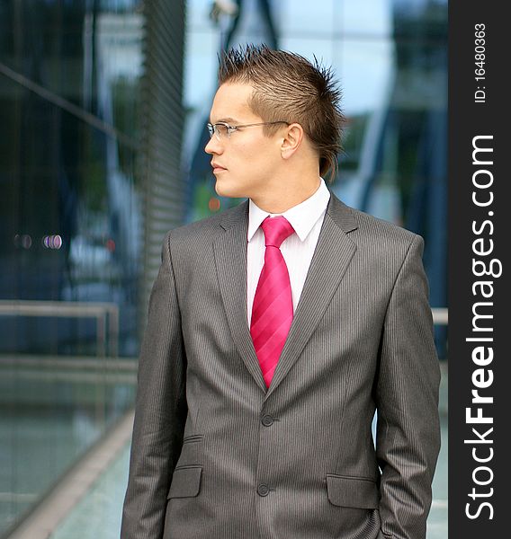 A young and handsome businessman in formal clothes and glasses. The image is taken on a modern background. A young and handsome businessman in formal clothes and glasses. The image is taken on a modern background.