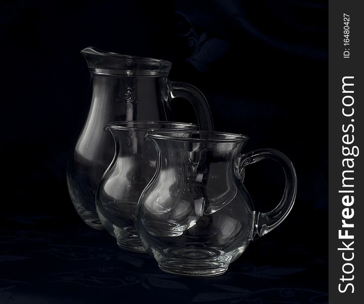 Pitchers three glass diverese capacity on a dark background. Pitchers three glass diverese capacity on a dark background