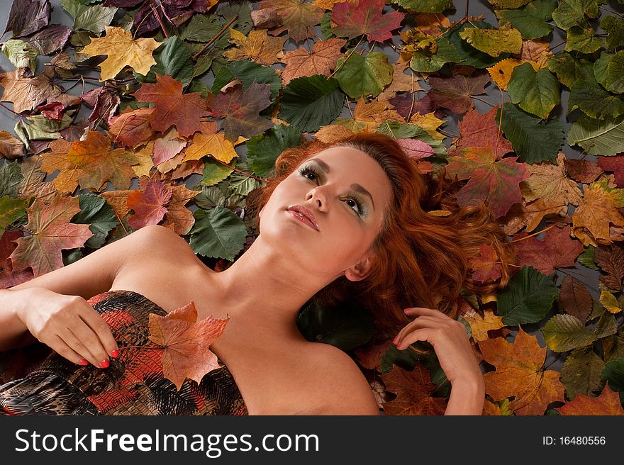 Portrait of a young and beautiful woman lying on a background with fallen autumn leaves. Portrait of a young and beautiful woman lying on a background with fallen autumn leaves.