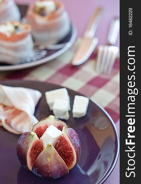 Fresh diced figs on the colorful plate with feta cheese and bacon on the background. Fresh diced figs on the colorful plate with feta cheese and bacon on the background