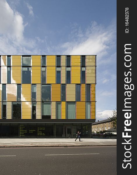 Modern office building with coloured facade panels and person walking by. Modern office building with coloured facade panels and person walking by