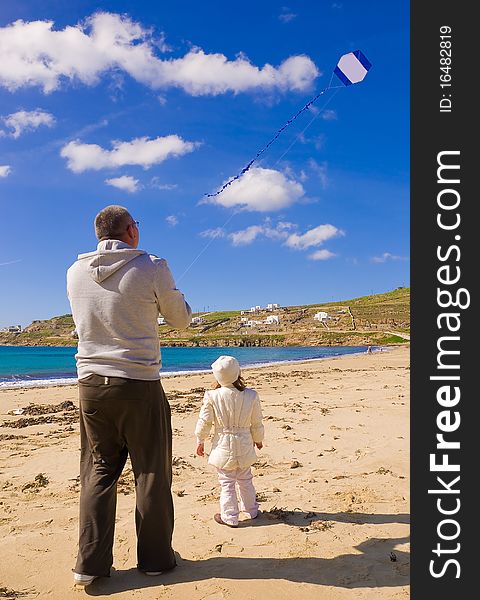 A little girl and dad run a kite in the sky with clouds on the beach near the sea. A little girl and dad run a kite in the sky with clouds on the beach near the sea