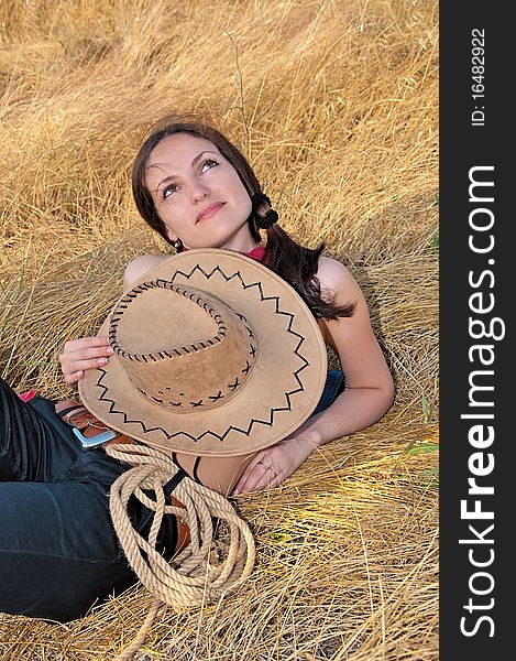 Beautiful woman lying in the straw with the hat