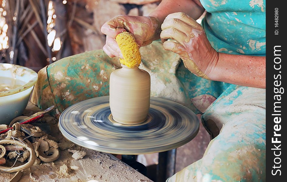 Close up of the hands of a potter creating a jug on the circle