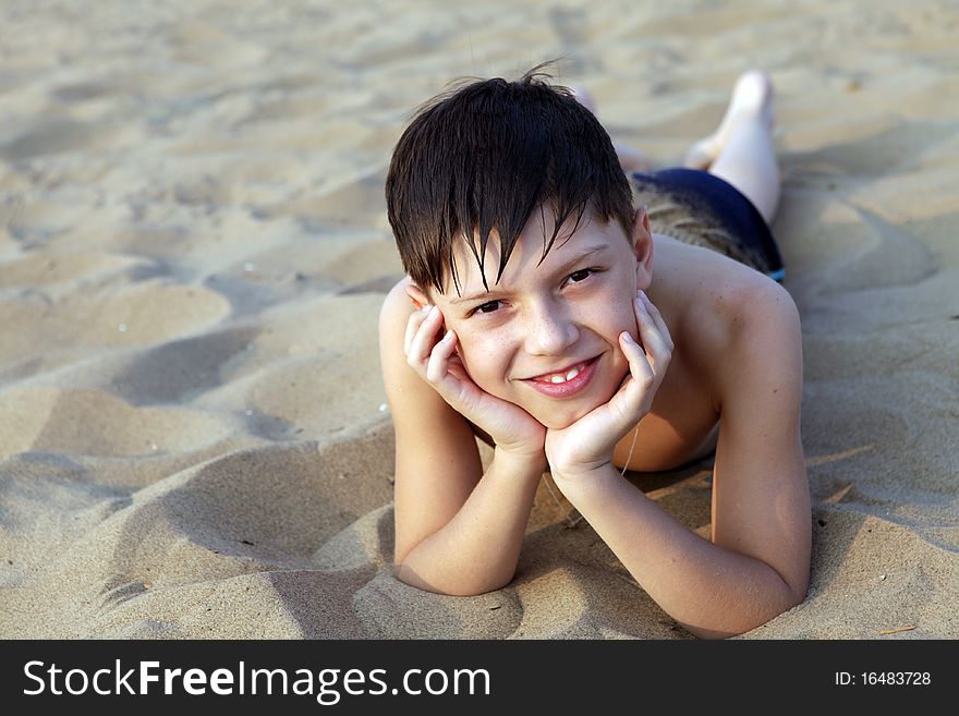 Smiling boy sunbathes on a beach