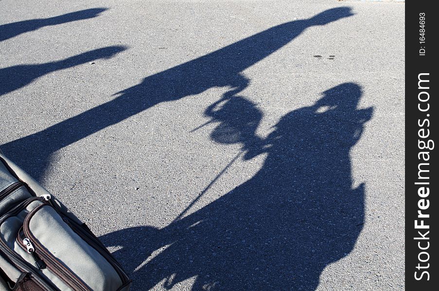 Shadow of a golfer pushing his golf cart. Shadow of a golfer pushing his golf cart