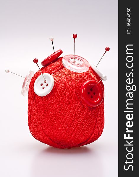 Red and white pins in red wool ball with buttons. Red and white pins in red wool ball with buttons
