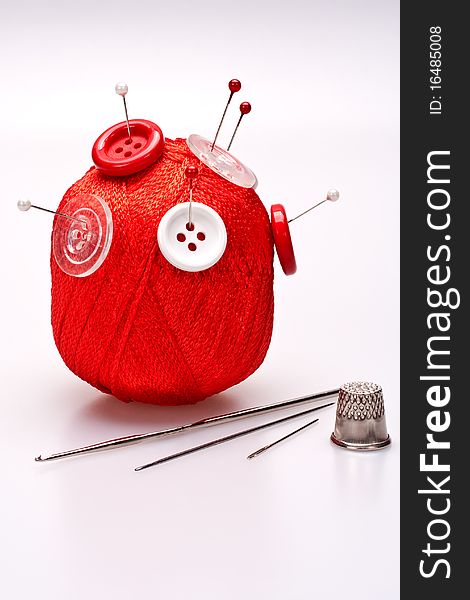 Red and white pins in red wool ball with buttons. Red and white pins in red wool ball with buttons