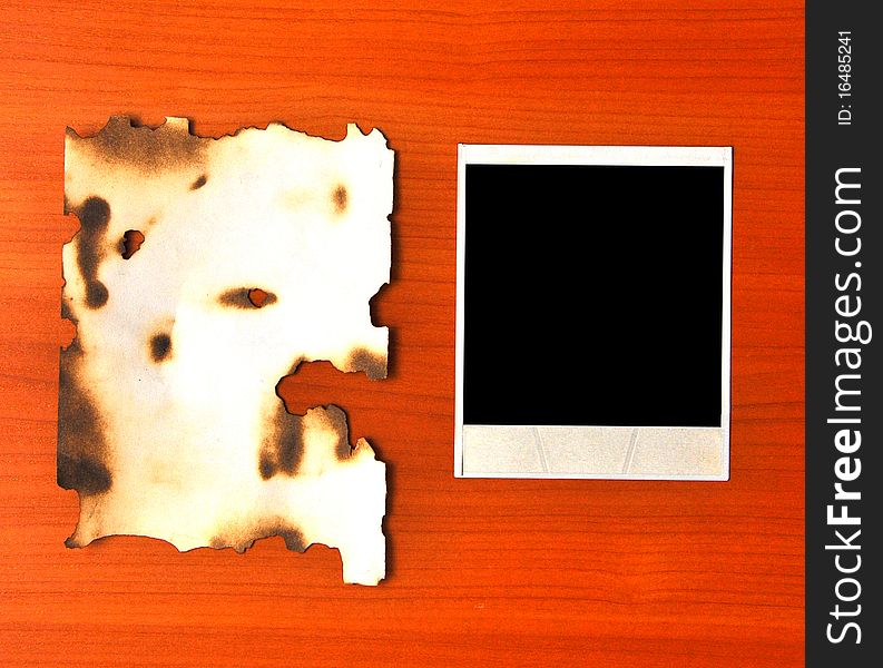 Old photos and burnt paper on a wooden background