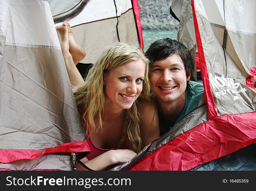 Couple laying in tent beside a riverf