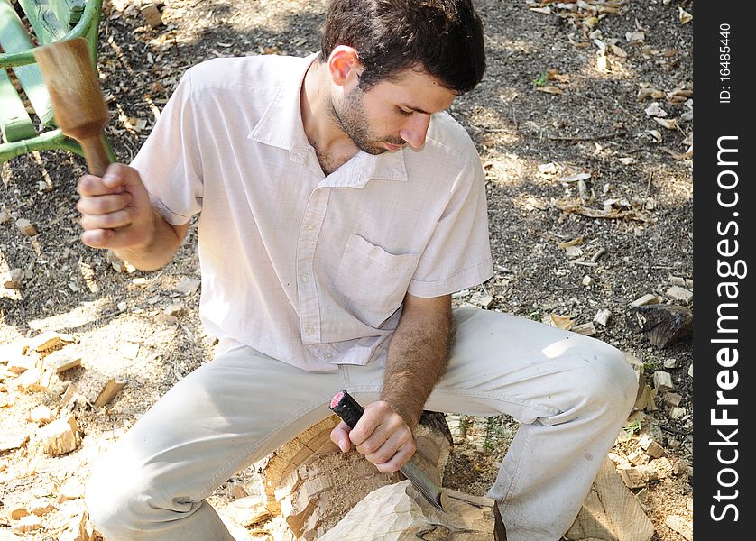 Young man sculpting wood material. Young man sculpting wood material