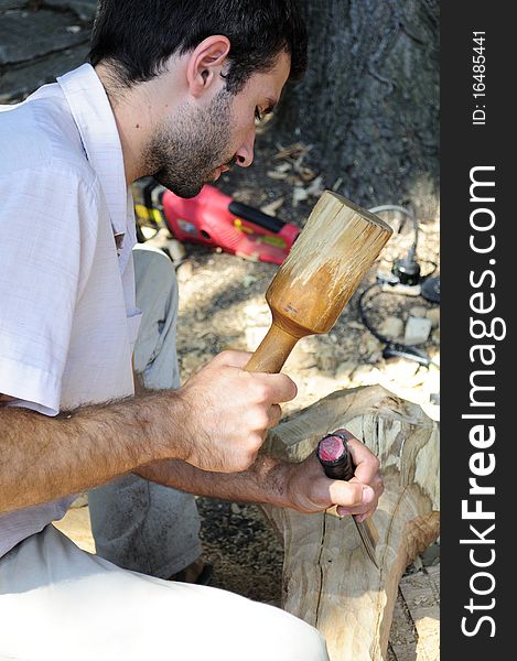 Young man sculpting wood material. Young man sculpting wood material