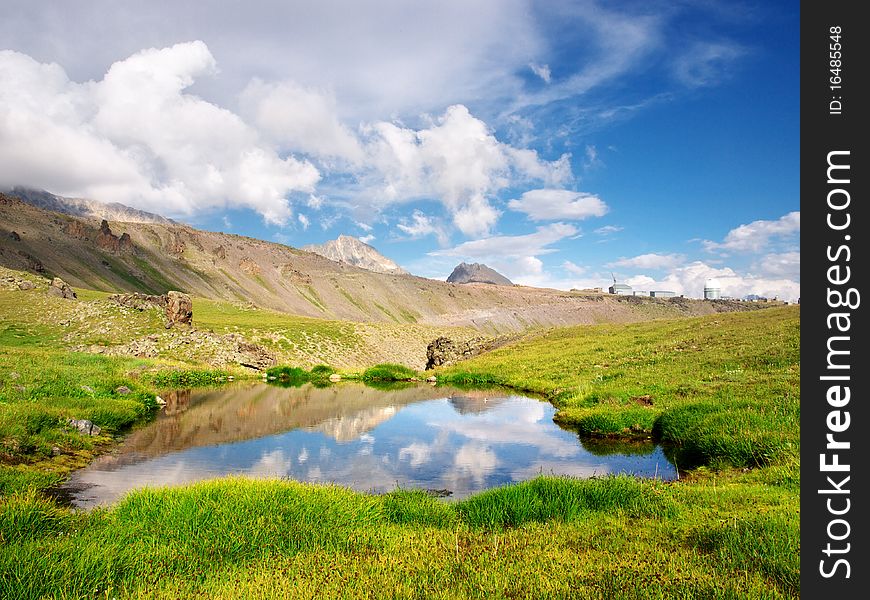 Lake amongst green meadow. Natural composition