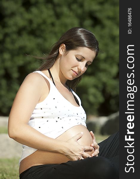 Beautiful pregnant woman relaxing in the park