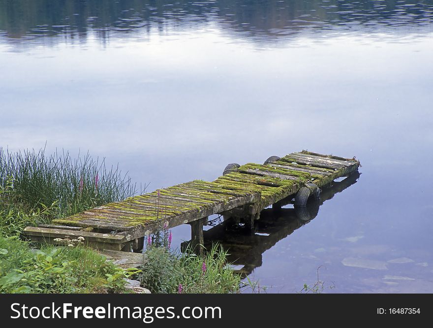 Old rustic pier on the shore of a lake