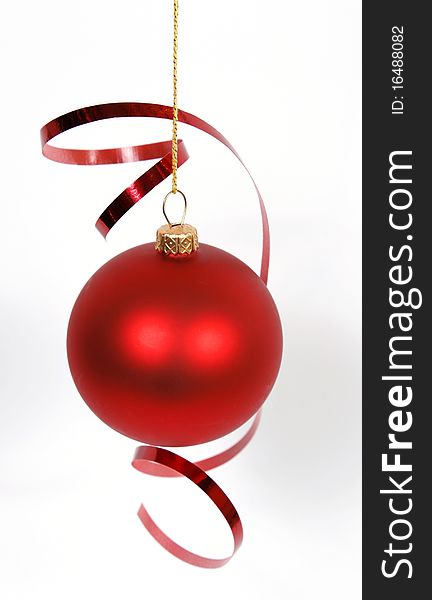 Hanging red glass ball with the ribbon on the white background. Hanging red glass ball with the ribbon on the white background