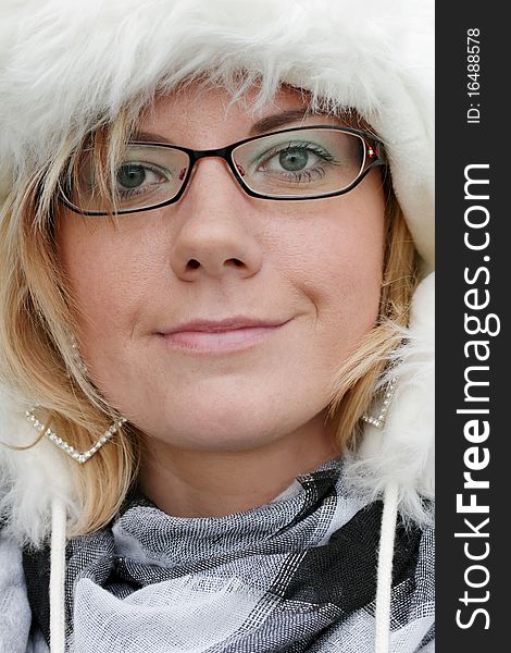 Cheeky portrait of a friendly smiling young woman with a white fur hat. Looking into the camera. Vertical Image. Cheeky portrait of a friendly smiling young woman with a white fur hat. Looking into the camera. Vertical Image.