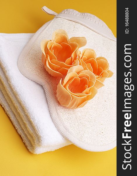 White towel with scented bath flowers and glove