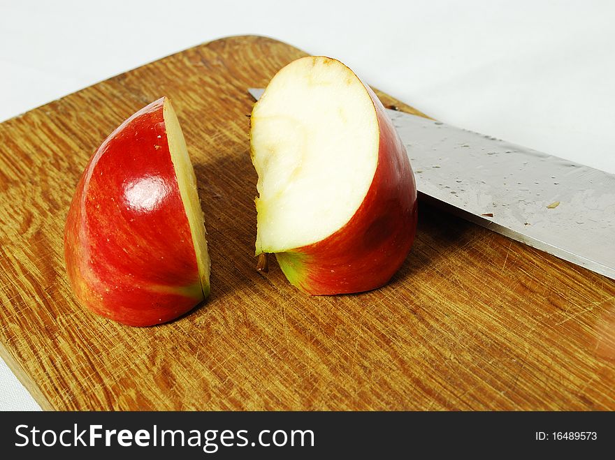 Apple is cut into pieces on a cutting board with a knife, white background, still life