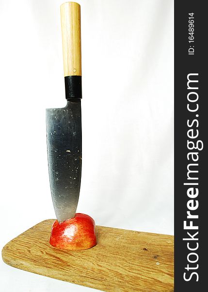 Half an apple in it plunged the knife, white background, still life, red juicy fruits of apple, colors of nature, food, juice, fruit, knife, cutting, cutting fruit, cutting board