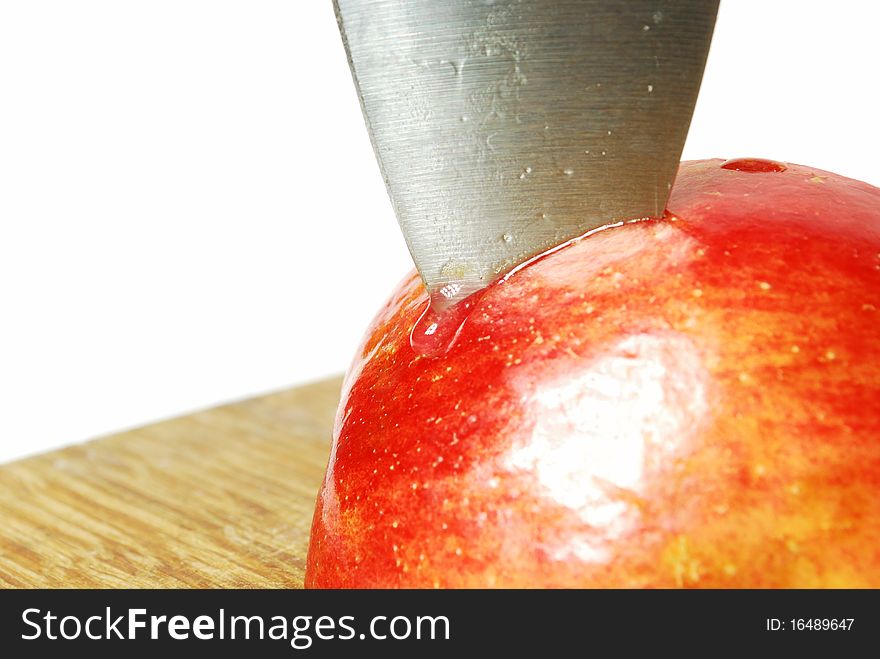 Apple on a cutting board in it plunged the knife on the end of the knife drops of juice, white background, still life, red juicy fruits of apple, colors of nature, food, juice, fruit, knife, cutting, cutting fruit, cutting board, a drop