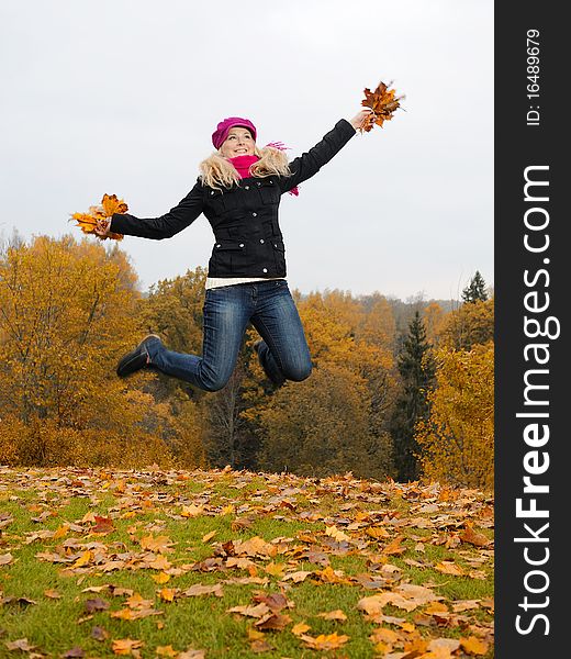 Beautiful Girl With Autumn Leafs In A Park Jumping