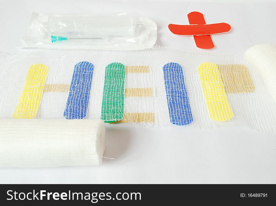 Help, the inscription is made of plaster, covered with a bandage on top from the bottom syringe packing bandage of plaster made of red cross, still life placed on a white background