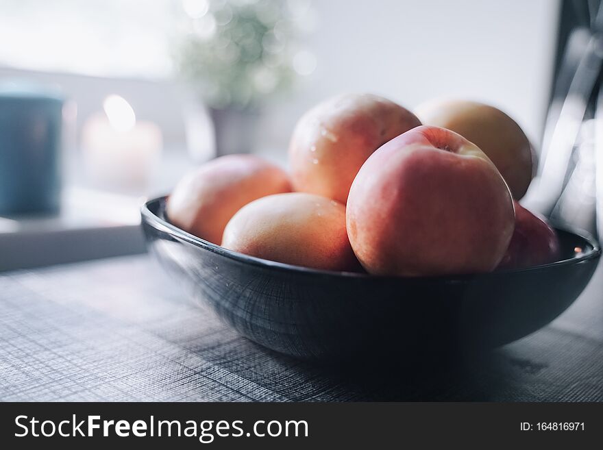 A Plate Of Peaches On The Table In Front Of The White Windowsill