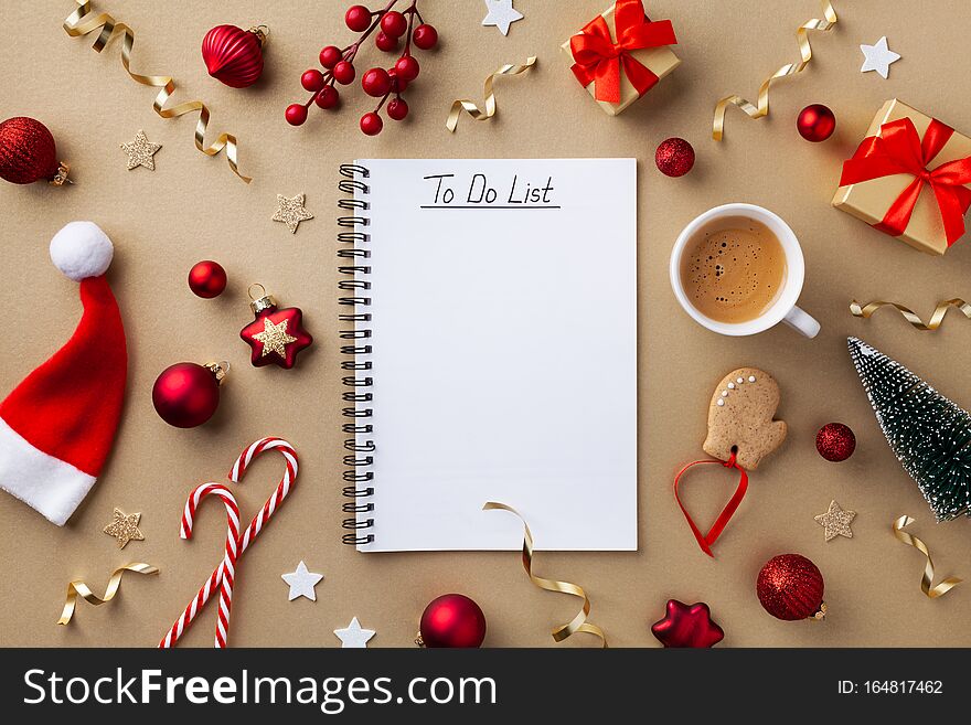 Cup of coffee, holiday decorations and notebook with to do list on golden background top view, Christmas planning concept.Flat lay