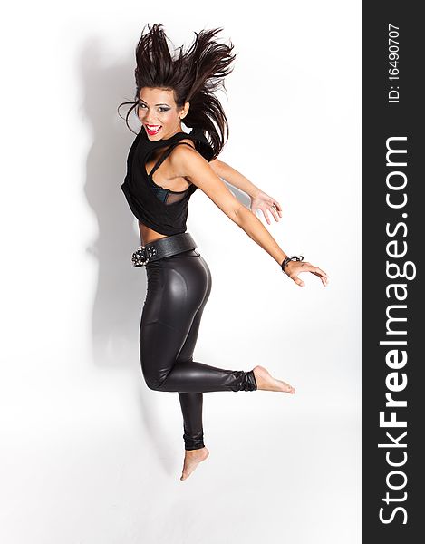 Beautiful female fashion model jumping happy - isolated on white wearing shiny black leggings