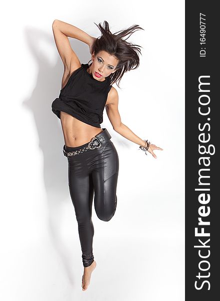 Beautiful female fashion model jumping happy - isolated on white wearing shiny black leggings