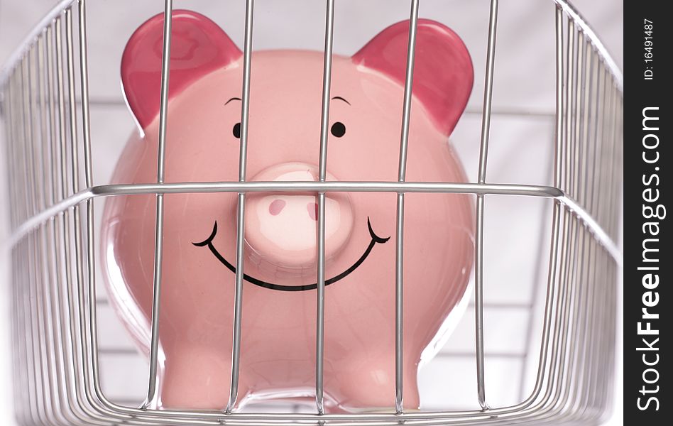 Piggy bank behind cage in studio. Piggy bank behind cage in studio