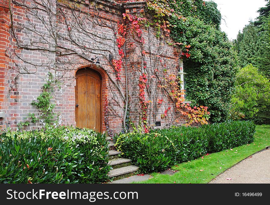 Early Autumn in an English with doorway through a red brick wall. Early Autumn in an English with doorway through a red brick wall