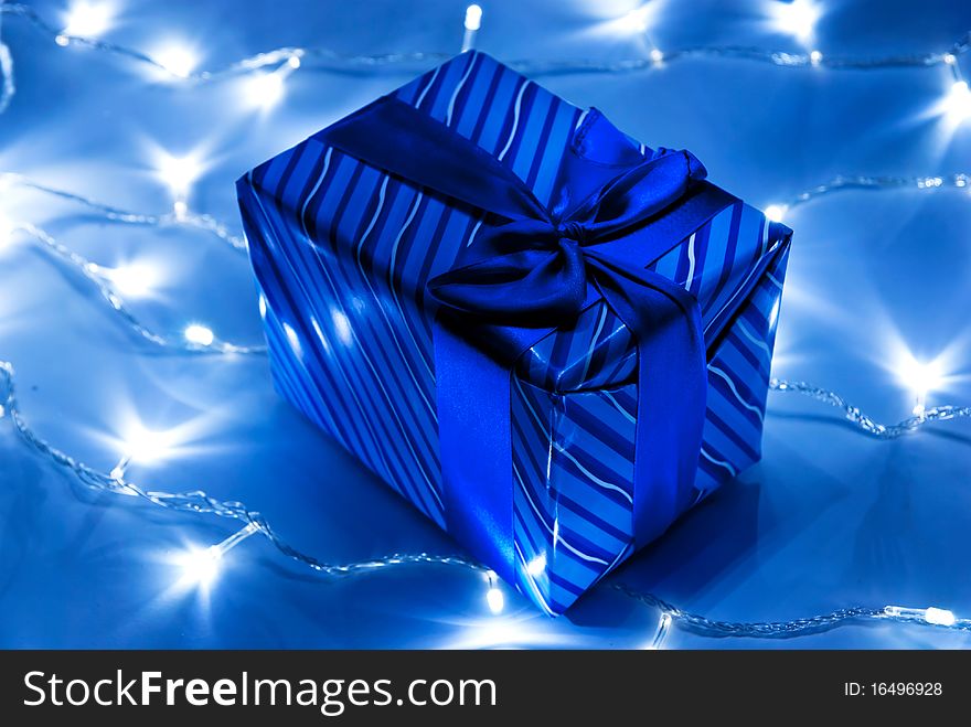 Blue gift box with garland background. Studio shot. Blue gift box with garland background. Studio shot