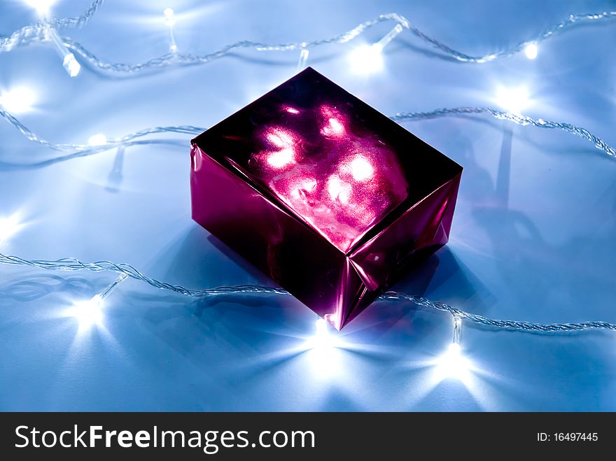 Red gift box and garland lights. Studio shot