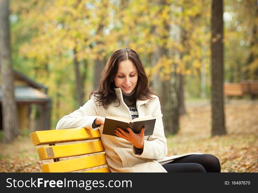 Pretty woman and book in autumn park