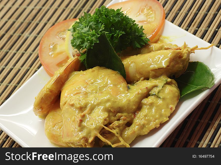 A dish of prawn in fermented durian sauce with sliced tomato and garnishing