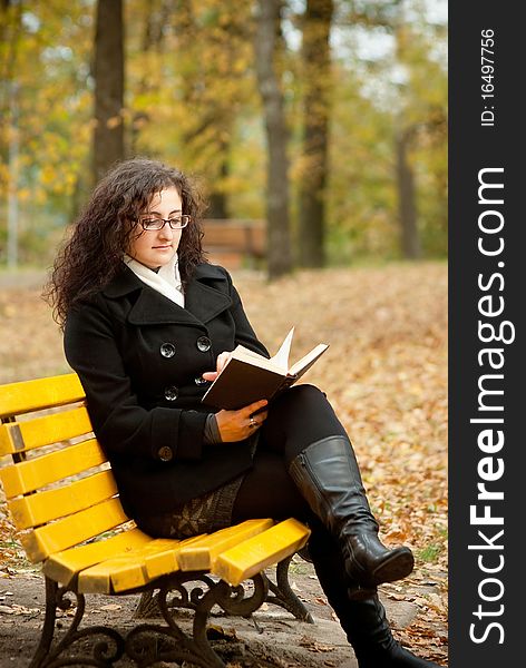 Young woman reading book on bench