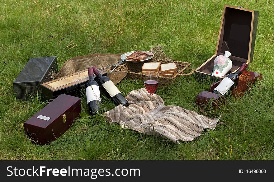 Picnic scene: wine bottles, glass, bread, wine boxes, still life