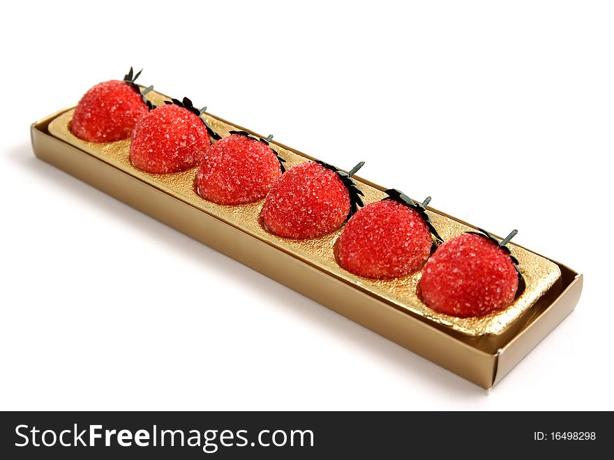 Marzipan strawberries in the golden box on white background.