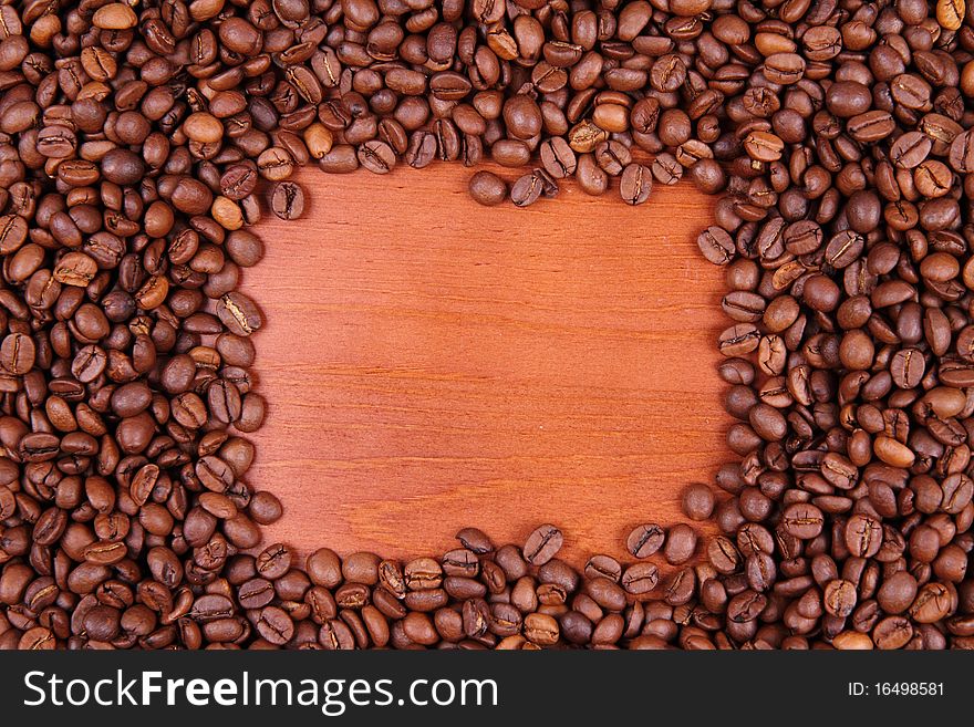 Coffee beans with wooden background in the middle with space for text. Coffee beans with wooden background in the middle with space for text