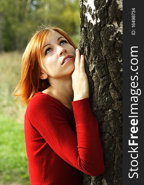 Beauty girl in red dress snuggle up to tree, half body, looking up