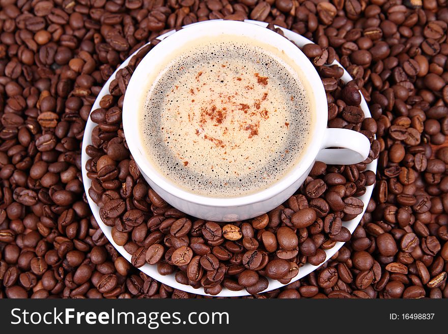 Cup of coffee with sprinkled with cinnamon with coffee beans around it