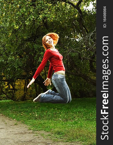 Young girl in red shirt and jeans jumping outdoor. Young girl in red shirt and jeans jumping outdoor